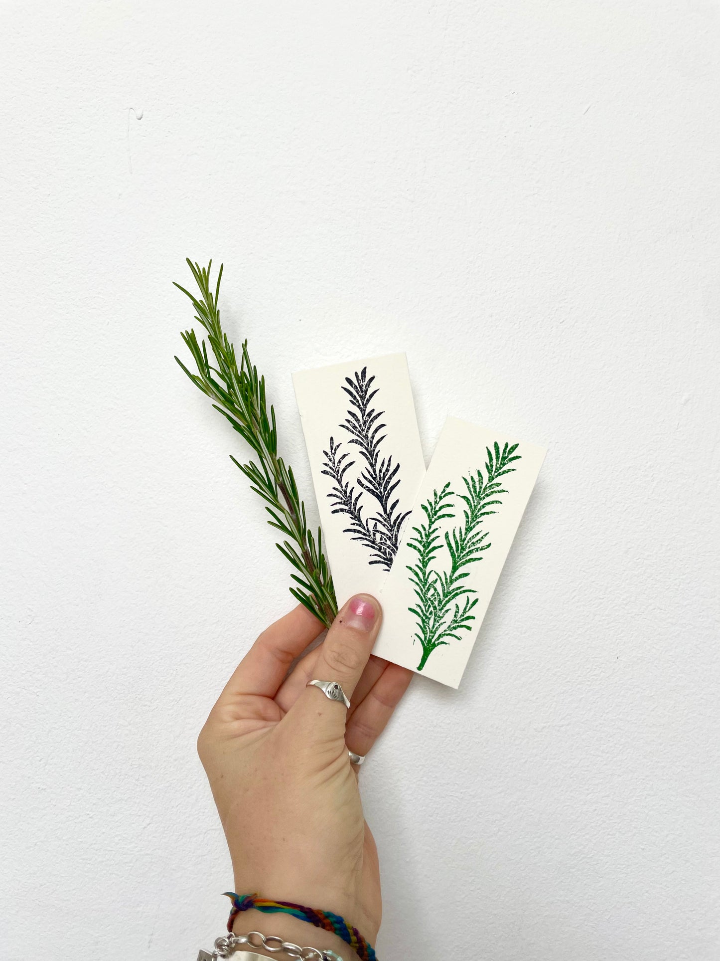 A lino print of a rosemary lavender sprig in black and white with a green version