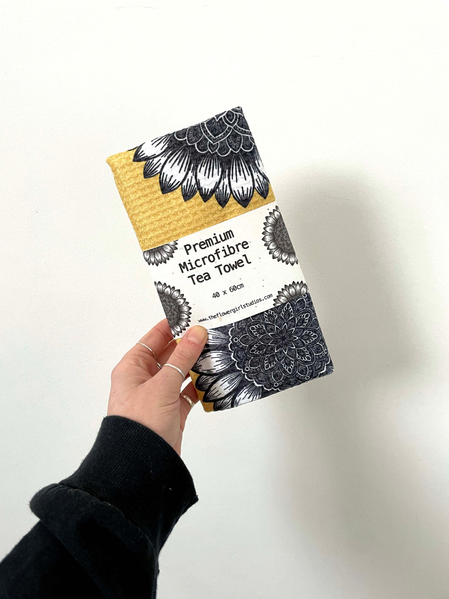 a microfibre waffle kitchen tea towel with a sunflower and mandala pattern in yellow, black, and gray colors.